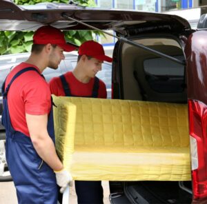 Günstig umziehen in Pfungstadt: Umzugshelfer laden ein gelbes Sofa in einen Transporter