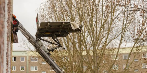 Möbellift zwischen kahlen Bäumen vor einem Gebäude – Möbellift in Pfungstadt