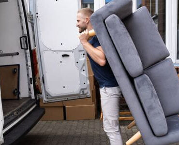 Möbellift Pfungstadt: Helfer tragen ein graues Sofa aus einem Transporter